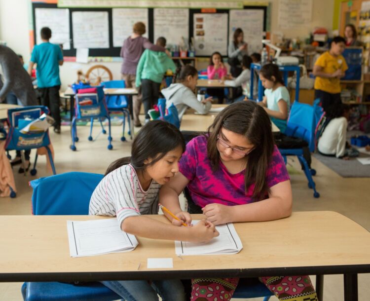 students at desk helping each other